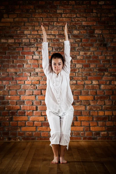 Kvinna utövar yoga mot tegelvägg — Stockfoto