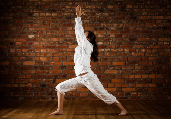 Woman exercising yoga against brick wall — Stock Photo, Image