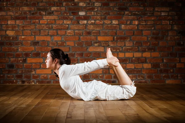 Woman exercising yoga against brick wall — Stock Photo, Image