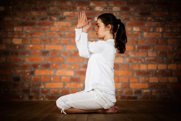 Mujer ejercitando yoga contra pared de ladrillo —  Fotos de Stock