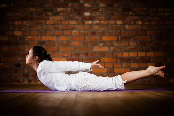 Woman exercising yoga against brick wall — Stock Photo, Image