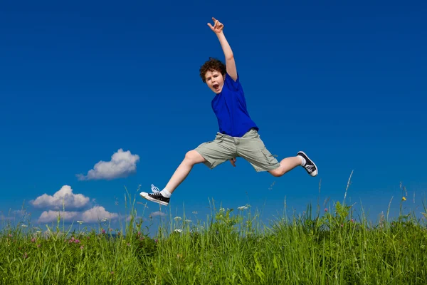 Хлопчик стрибає, біжить проти блакитного неба — стокове фото