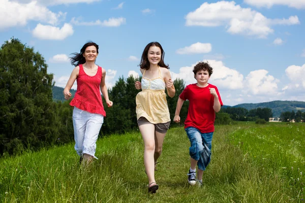 Actieve familie - moeder en kinderen lopen, springen buiten Stockfoto