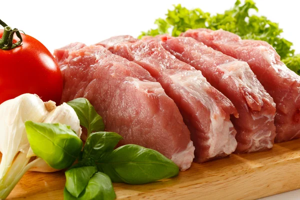 Raw pork on cutting board and vegetables — Stock Photo, Image