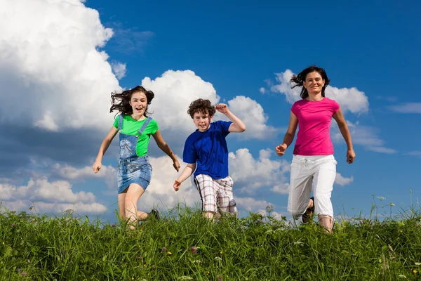 Famille active - mère et enfants courant, sautant en plein air — Photo