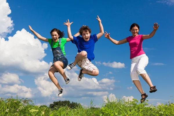 Famille active - mère et enfants courant, sautant en plein air — Photo