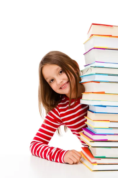 Mädchen blickt hinter Bücherstapel auf weißem Hintergrund lizenzfreie Stockbilder