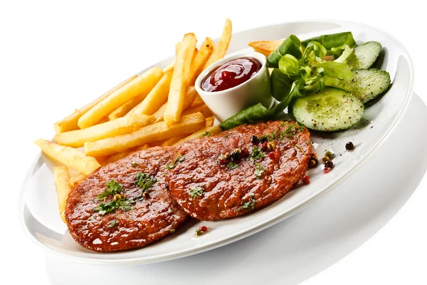 Grilled steaks, French fries and vegetables — Stock Photo, Image