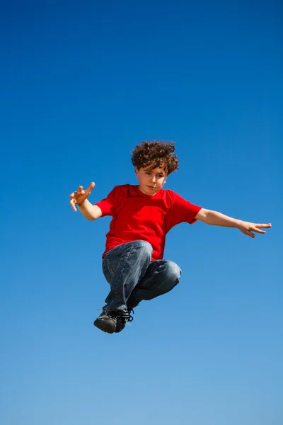 Rapaz a saltar, a correr contra o céu azul — Fotografia de Stock