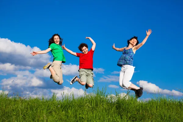 Familia activa - madre e hijos corriendo, saltando al aire libre —  Fotos de Stock