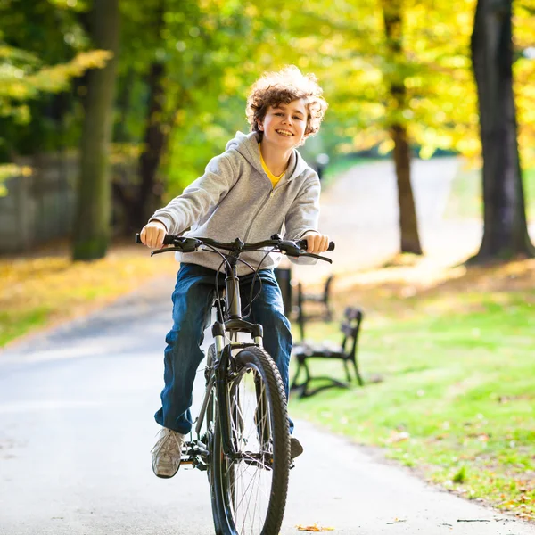 Urban biking - teenage boy riding bike in city park — Stock Photo, Image