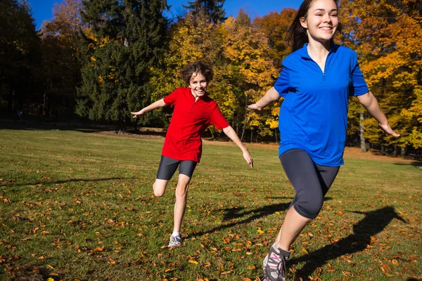 Dívka a chlapec běh, skákání v parku — Stock fotografie