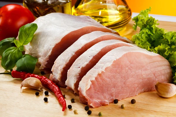 Syrové vepřové maso na řezací desce a zelenině — Stock fotografie
