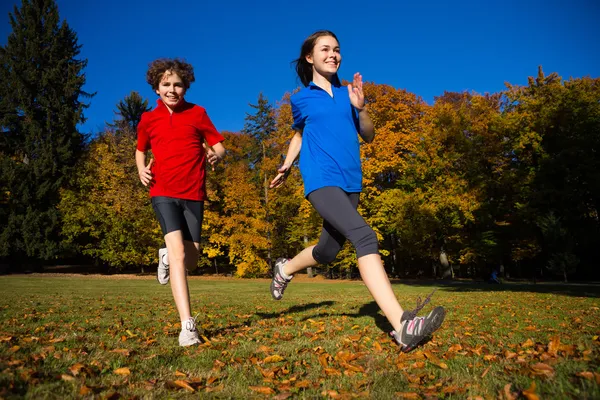 Mädchen und Junge rennen, springen im Park — Stockfoto