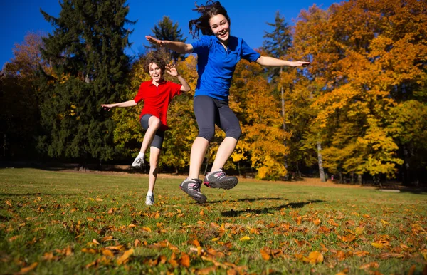 Chica y niño corriendo, saltando en el parque —  Fotos de Stock
