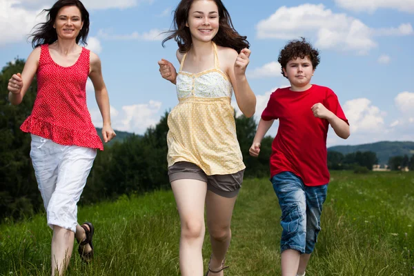 Famille active - mère et enfants courant, sautant en plein air — Photo