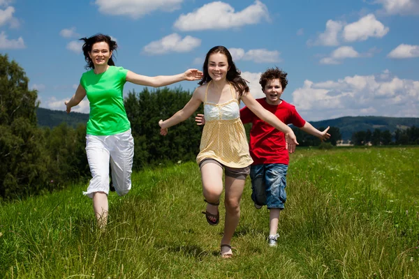 Aktivní rodina - matka a děti, běh, skákání venkovní Stock Obrázky
