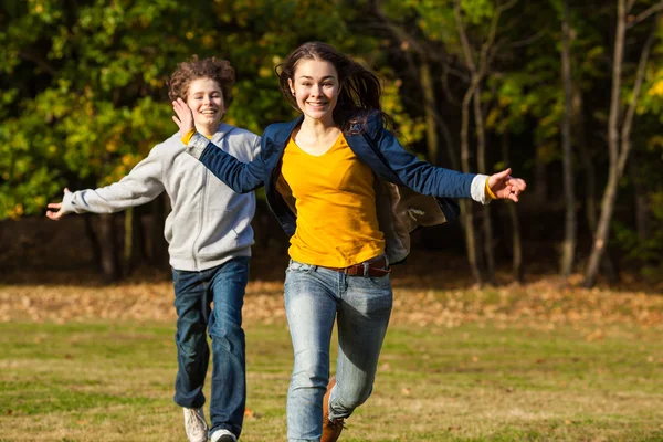 Ragazza e ragazzo correre, saltare nel parco — Foto Stock