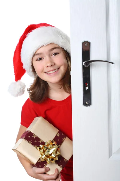 Menina com chapéu de Papai Noel espreitando atrás da porta — Fotografia de Stock