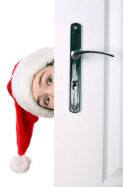 Ragazza con cappello di Babbo Natale sbirciando dietro la porta — Foto Stock
