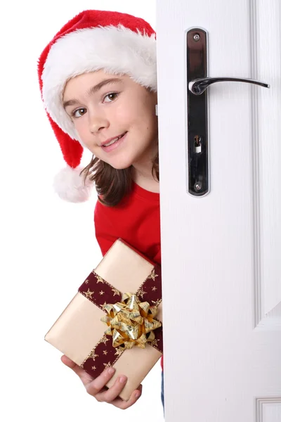 Fille avec chapeau de Père Noël regardant derrière la porte — Photo