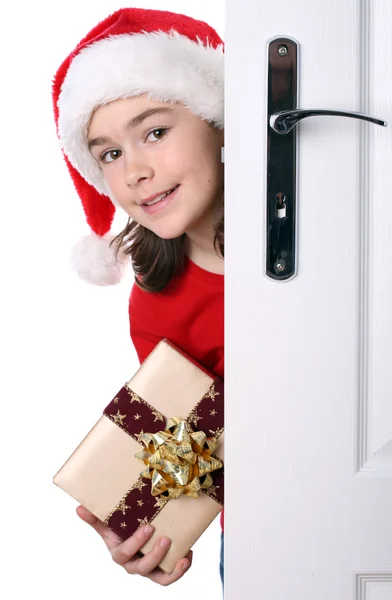 ドアの後ろにピーク サンタさんの帽子の少女 — ストック写真