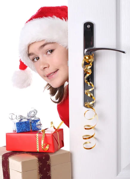 Menina com chapéu de Papai Noel espreitando atrás da porta — Fotografia de Stock