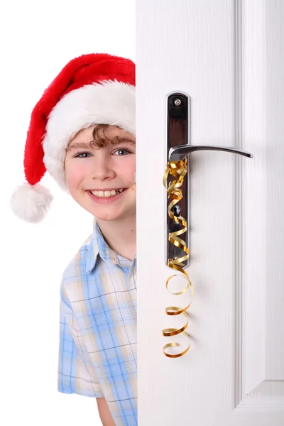 Kapının arkasına bakmak Noel Baba'nın şapkalı çocuk — Stok fotoğraf