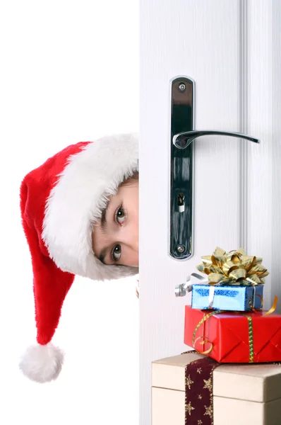 Ragazza con cappello di Babbo Natale sbirciando dietro la porta — Foto Stock