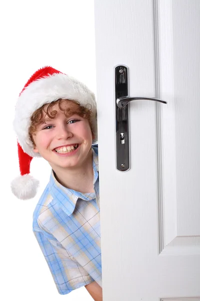 Kapının arkasına bakmak Noel Baba'nın şapkalı çocuk — Stok fotoğraf