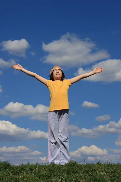 Dívka na zelené louce proti modré obloze — Stock fotografie