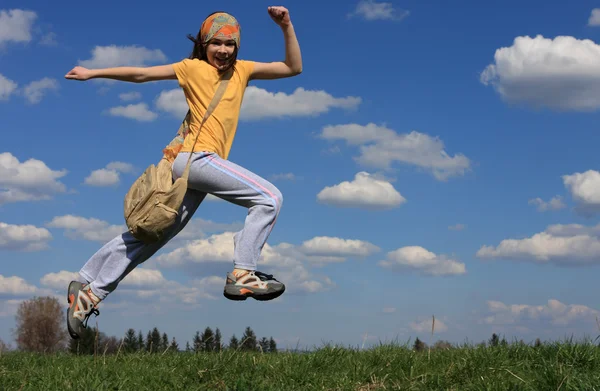Meisje uitgevoerd op groene weide tegen blauwe hemel — Stockfoto