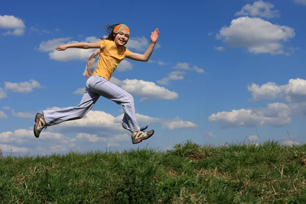 Девушка бежит по зеленому лугу против голубого неба — стоковое фото
