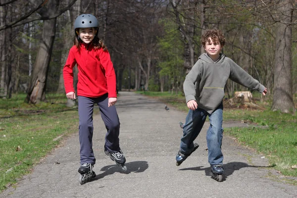 Joven niña y niño en patines — Foto de Stock