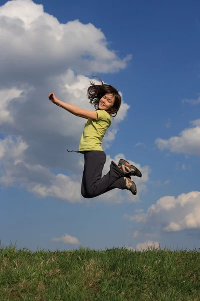 Fille sautant sur la prairie verte — Photo