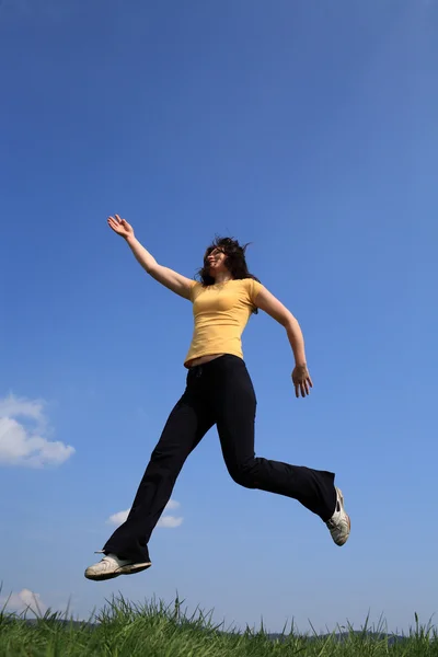 Menina pulando no prado verde — Fotografia de Stock