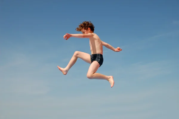 Pojken hoppar på stranden — Stockfoto