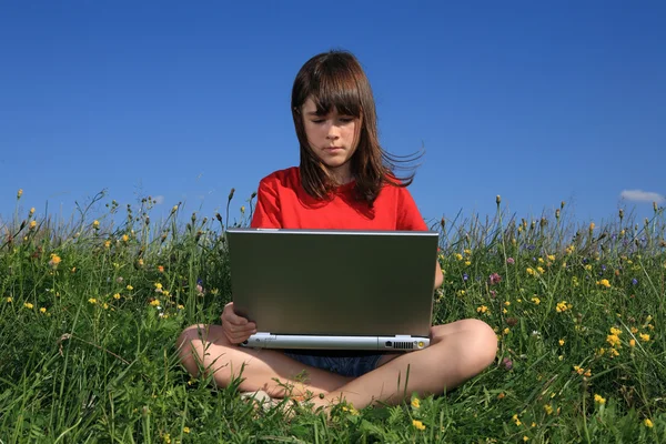 Meisje met laptop op groene weide — Stockfoto