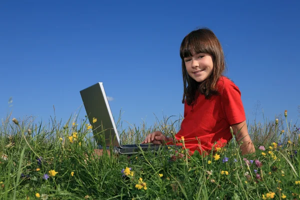 Flicka med laptop på grön äng — Stockfoto