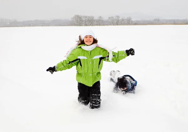 Chica jugando en el campo cubierto de nieve — Foto de Stock