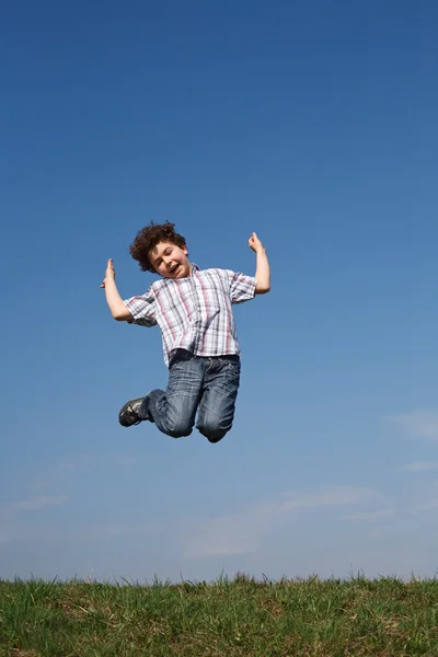 Niño saltando contra el cielo azul —  Fotos de Stock