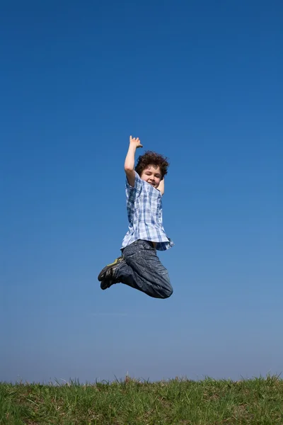 Junge springt gegen blauen Himmel — Stockfoto