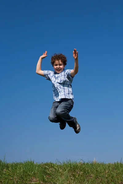 Junge springt gegen blauen Himmel — Stockfoto