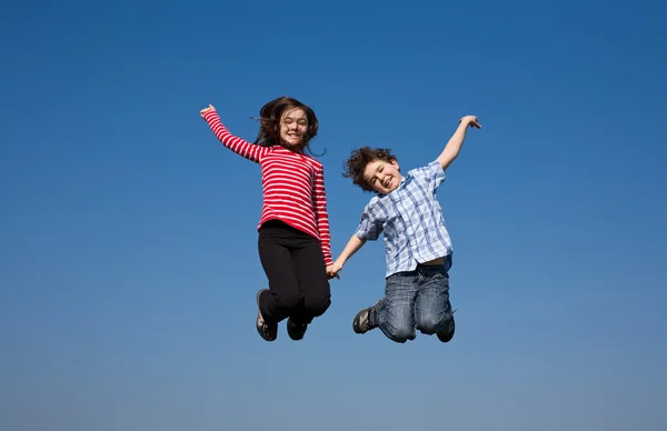 Girl and boy jumping outdoor — Stock Photo, Image