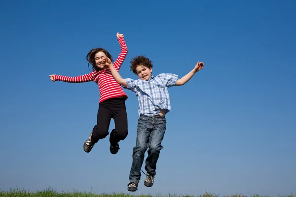 Girl and boy jumping outdoor — Stock Photo, Image