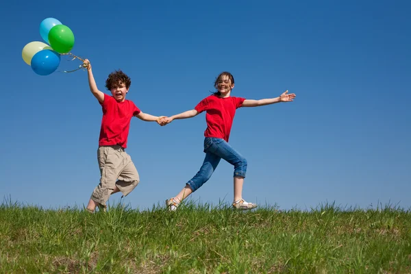 Niños sosteniendo globos, jugando al aire libre —  Fotos de Stock