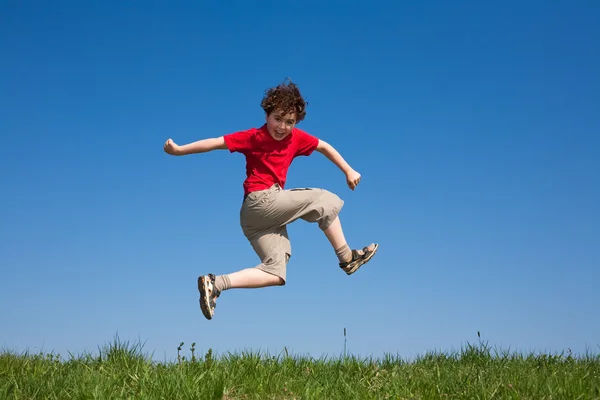 Fiú ellen kék égen jumping — Stock Fotó