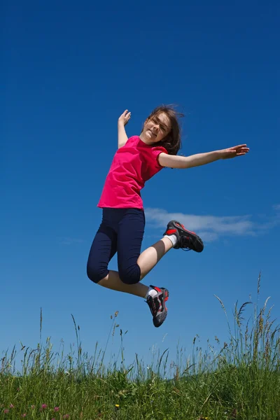 Dívka skákání a běží na zelené louce — Stock fotografie