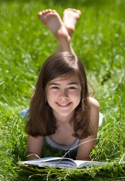 Meisje liggen op groene weide lezen van boek — Stockfoto