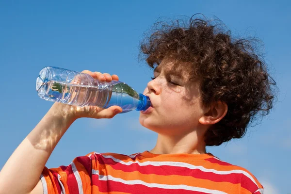 Boy drinking water against blue sky — Stock Photo, Image